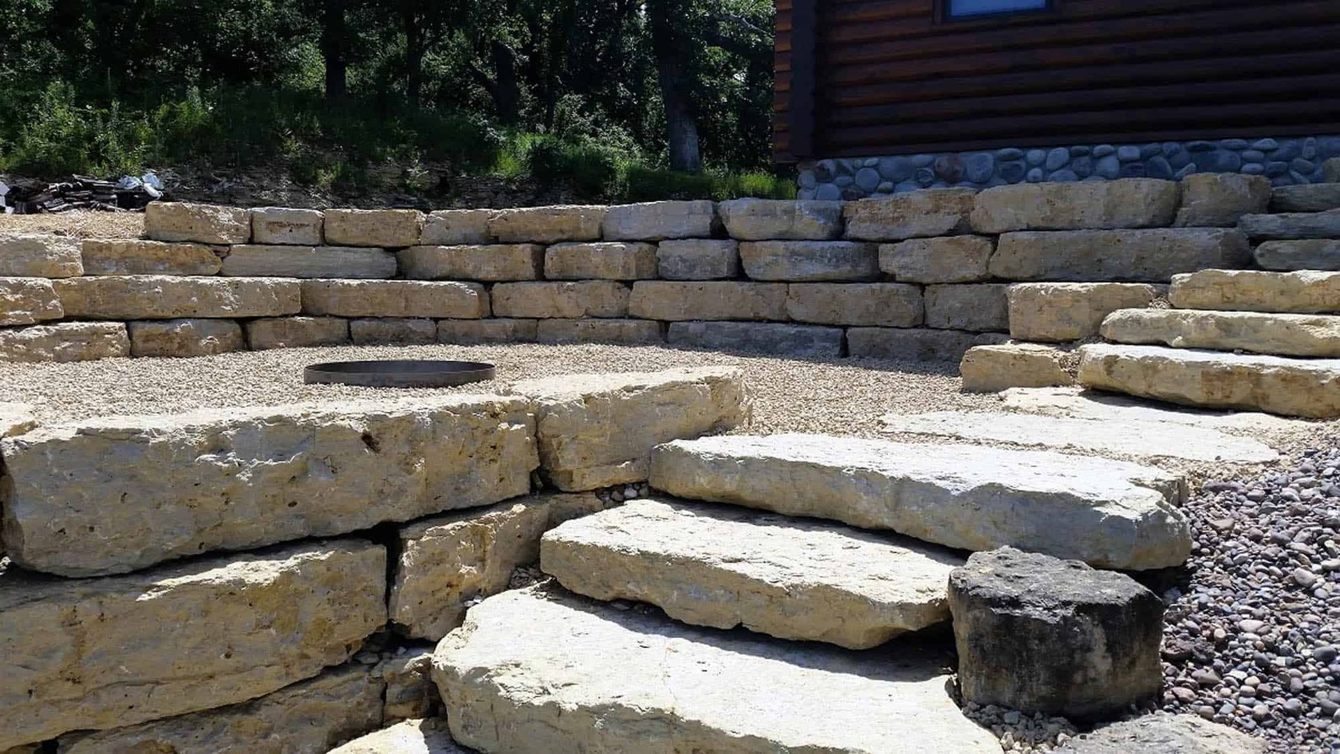 A stone wall with steps leading up to it in front of a house.