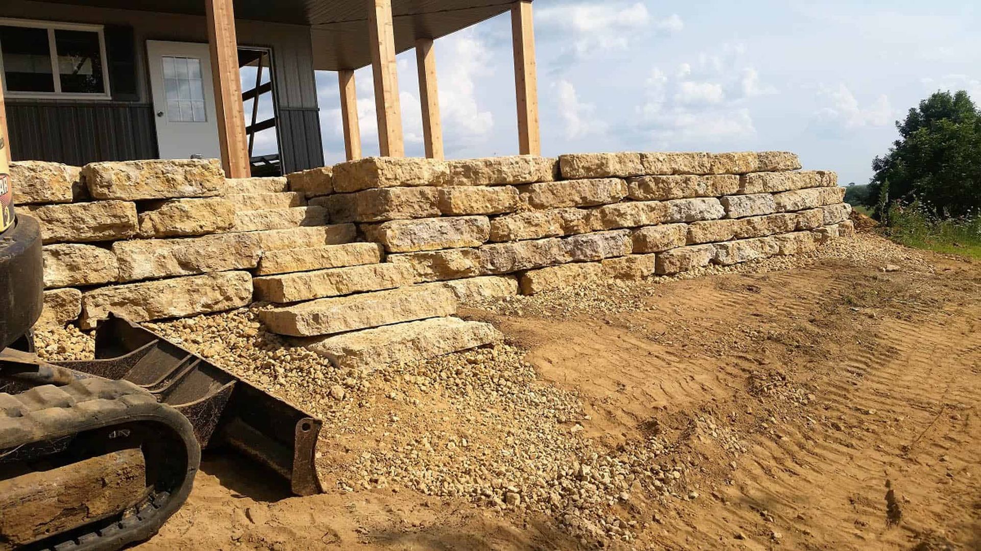 A large stone wall is being built in front of a house.