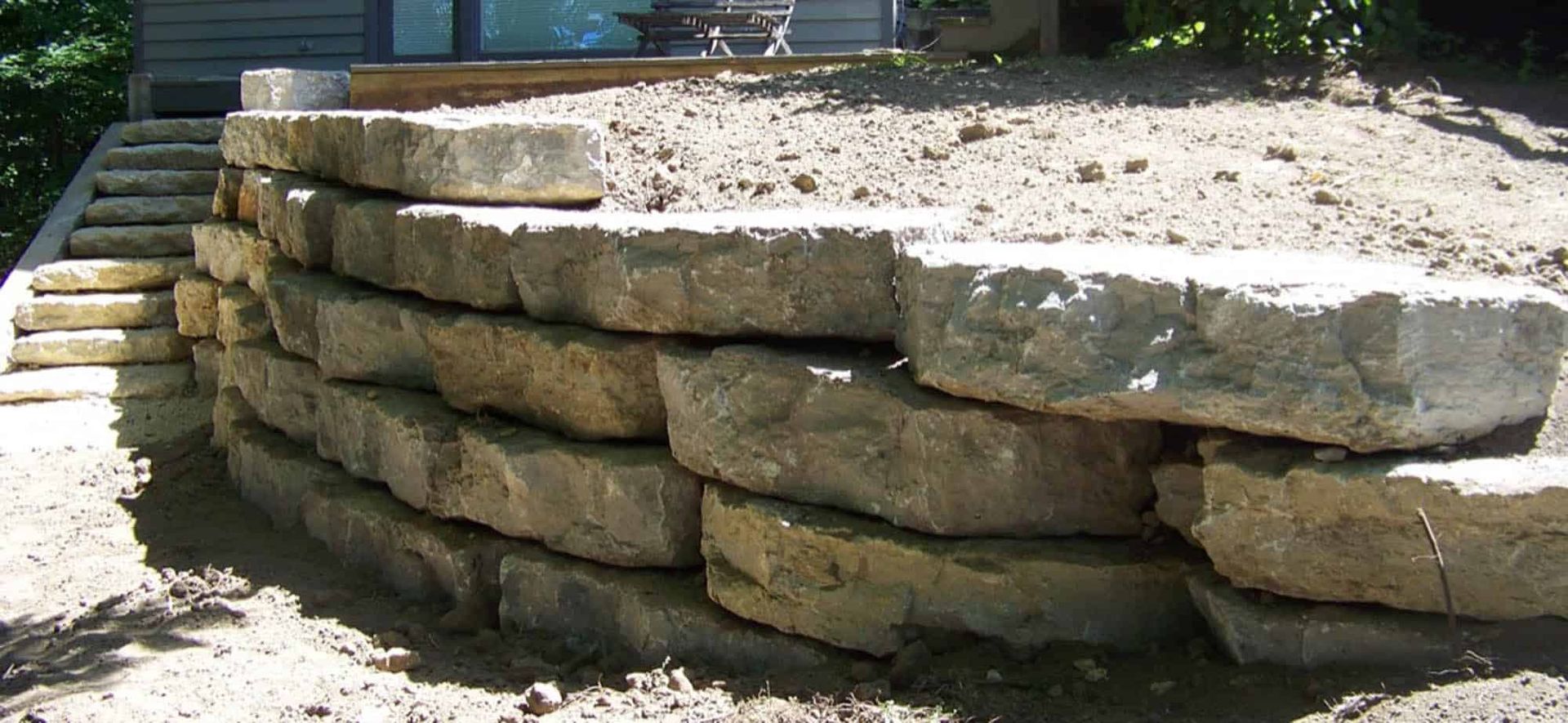 A stone wall is being built in front of a house