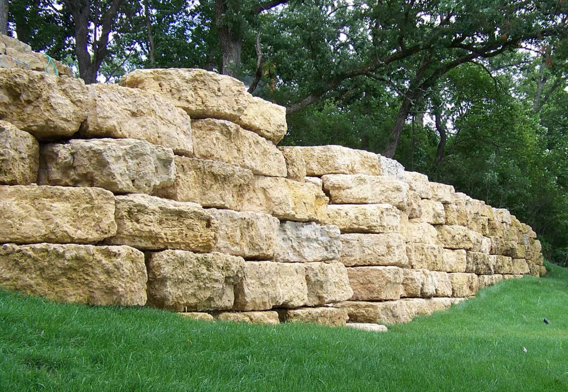 A large pile of rocks is sitting on top of a lush green field.
