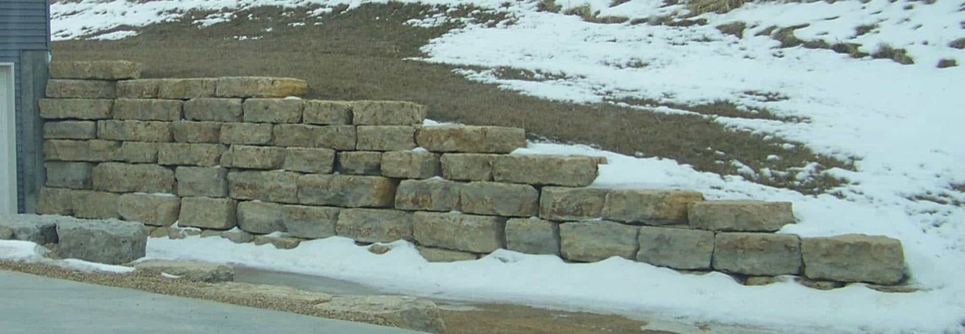 A brick wall with snow on the ground behind it