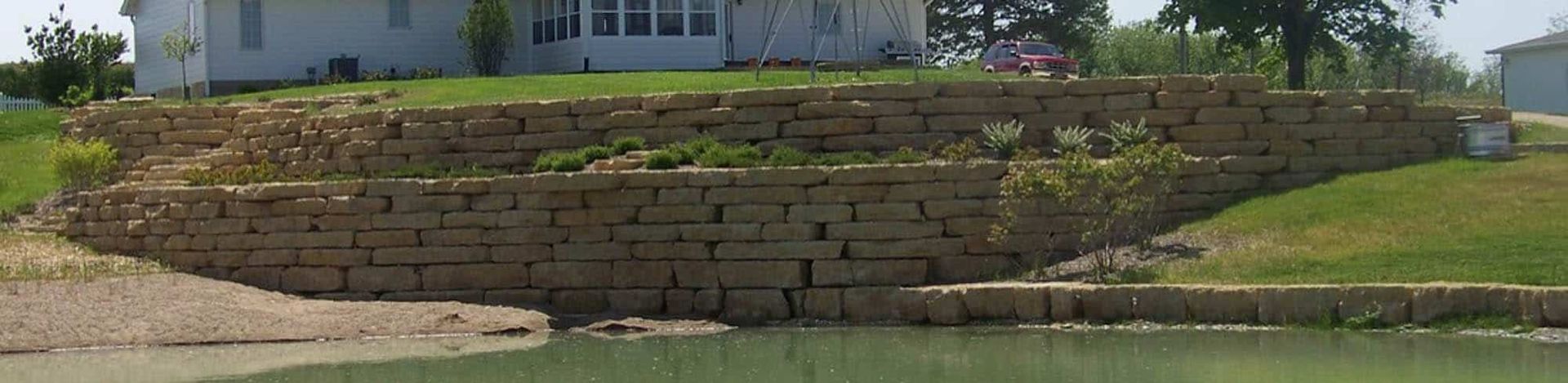 A house is sitting on top of a hill next to a pond.