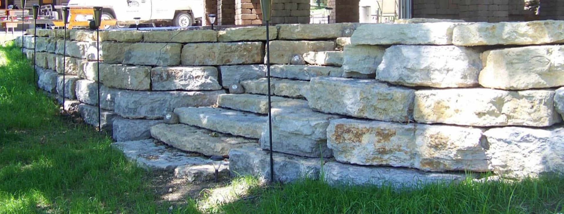 A stone wall is sitting in the grass in front of a house.