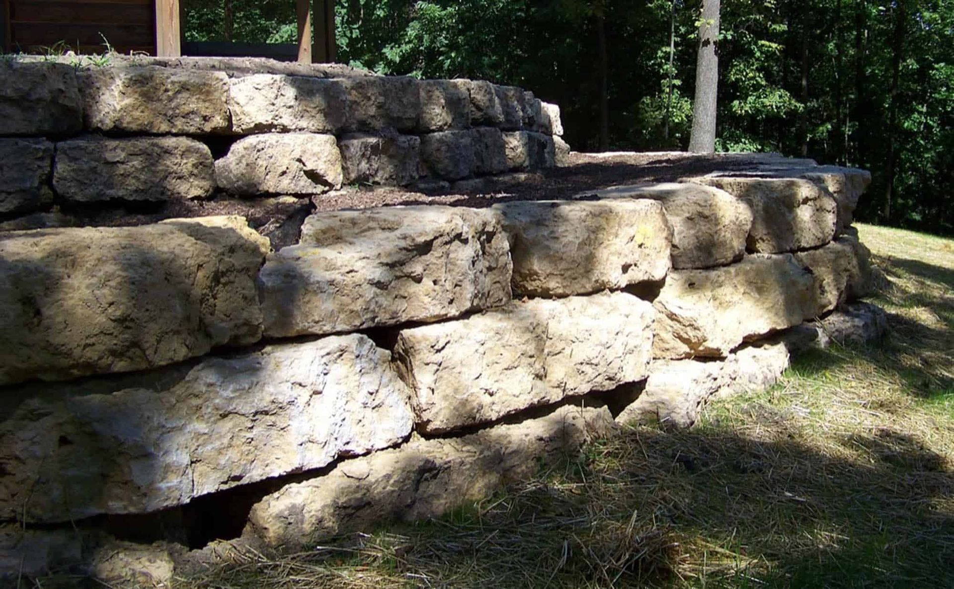 A large stone wall is sitting on top of a grassy hill