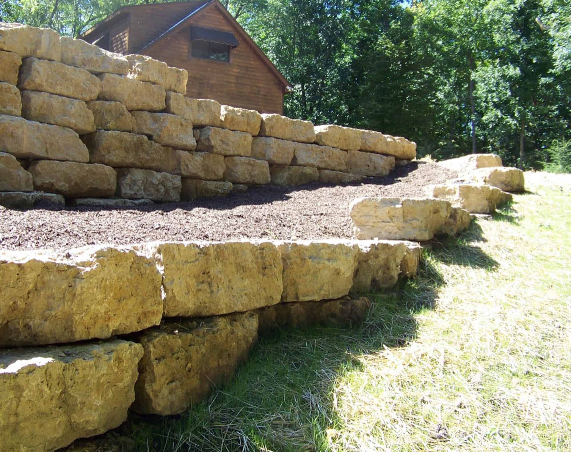 A large stone wall with a house in the background