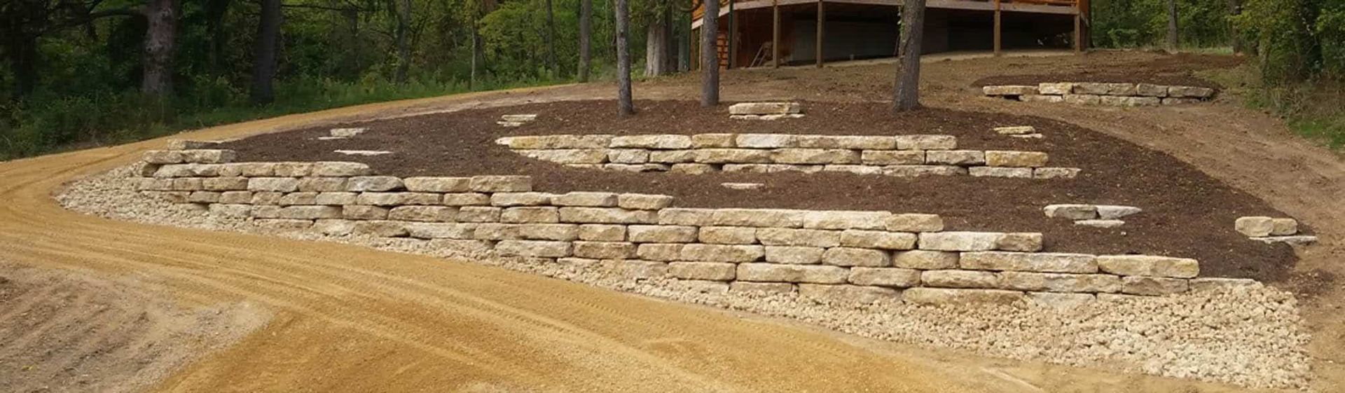 A dirt road with a stone wall on the side of it.