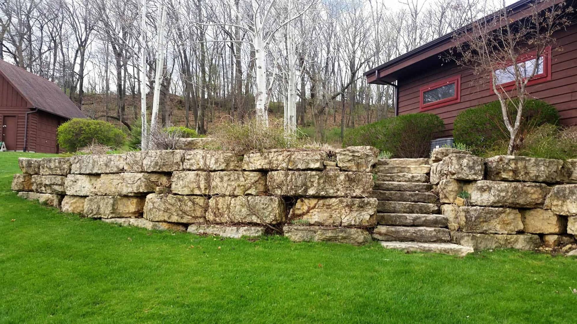 A large stone wall with stairs leading up to a house.