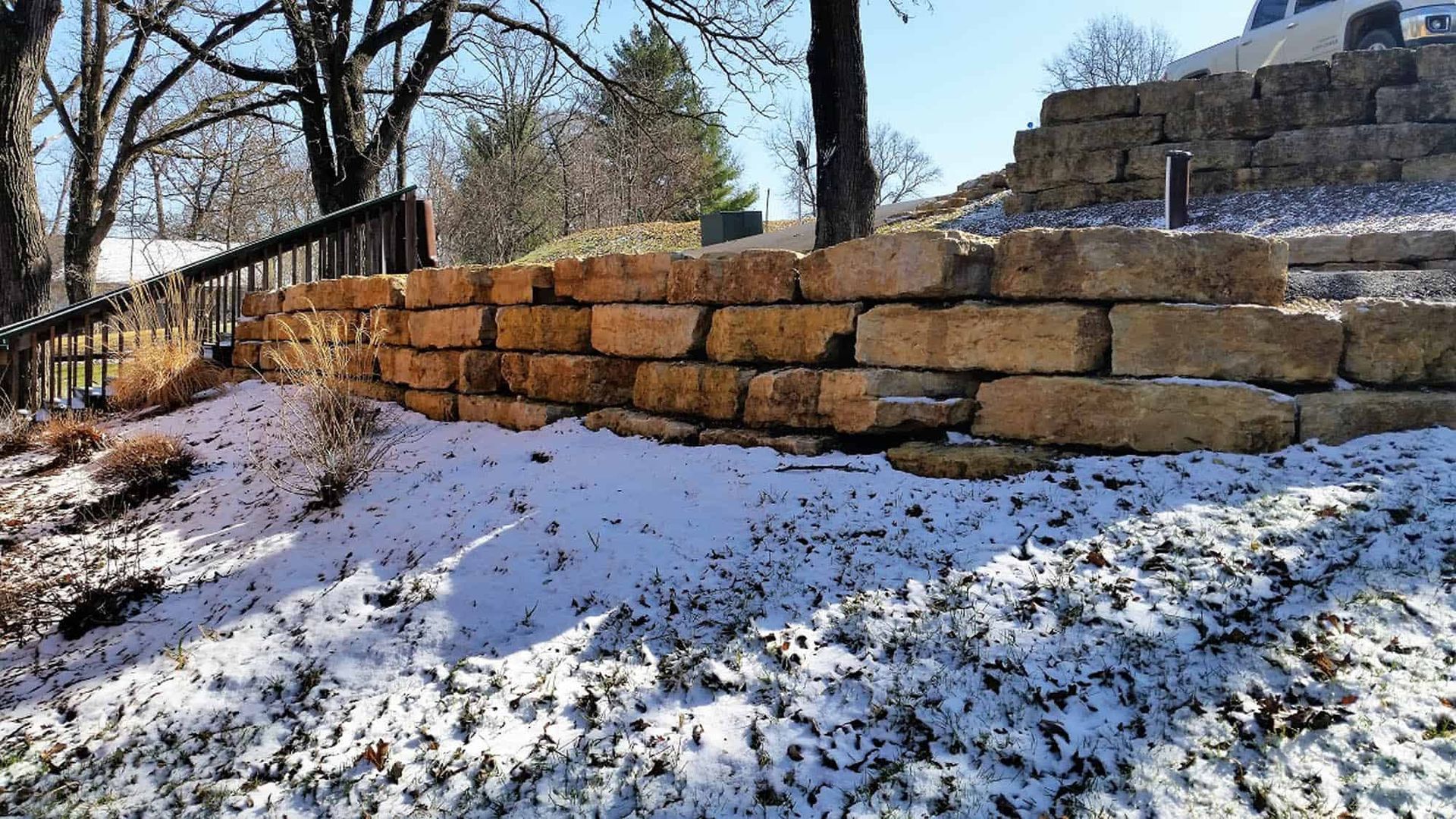 A stone wall with snow on the ground in front of it