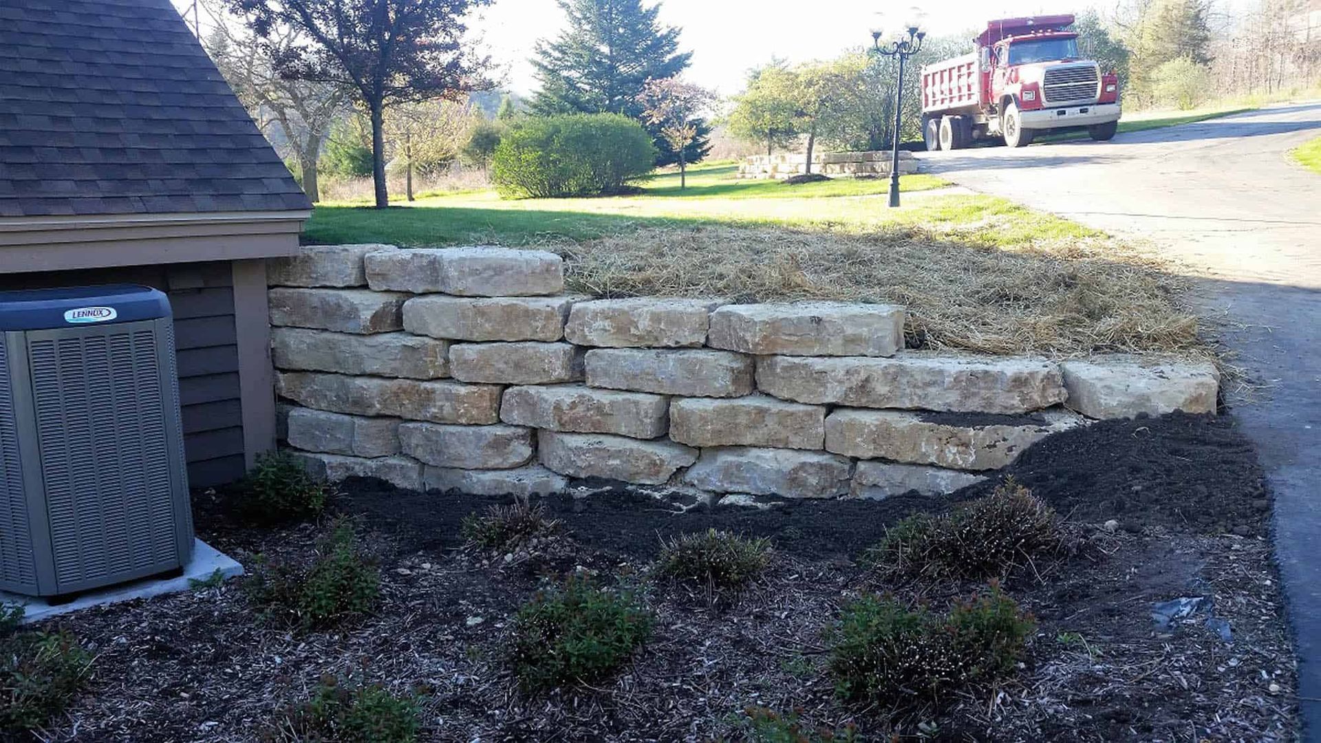 A truck is driving down a road next to a brick wall