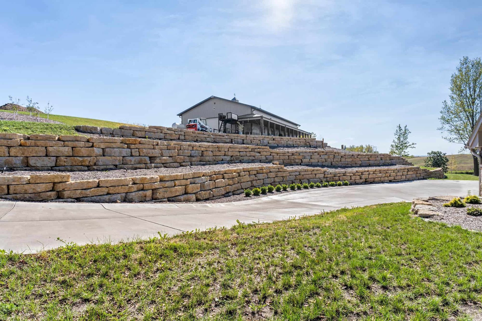 A large stone wall is surrounding a house on a hill.