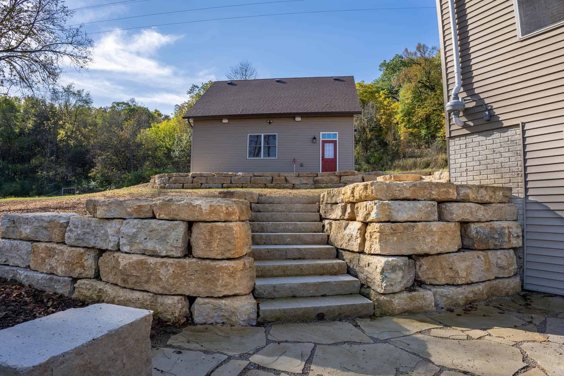 A house with a stone wall and stairs leading up to it.