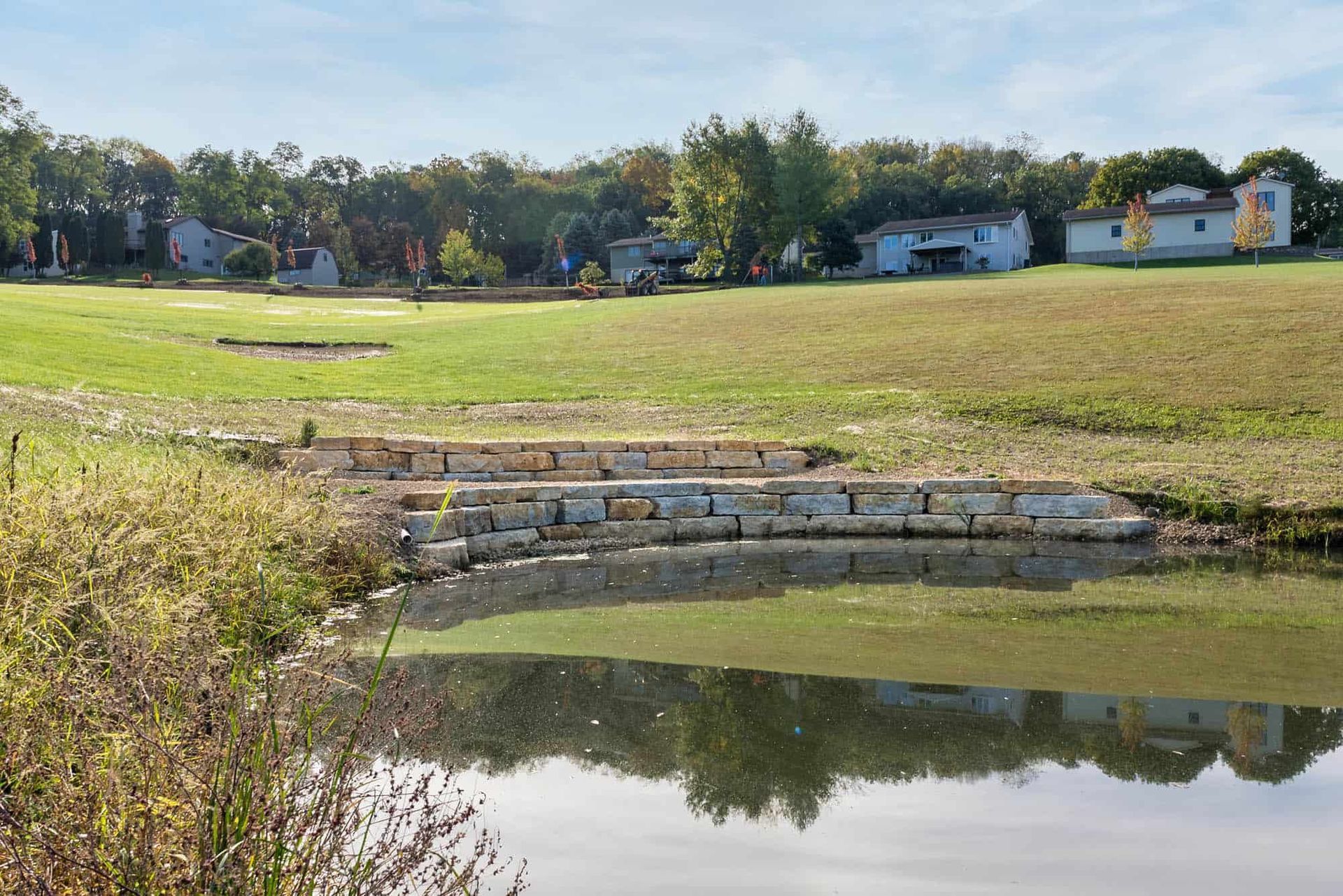 There is a pond in the middle of a grassy field.