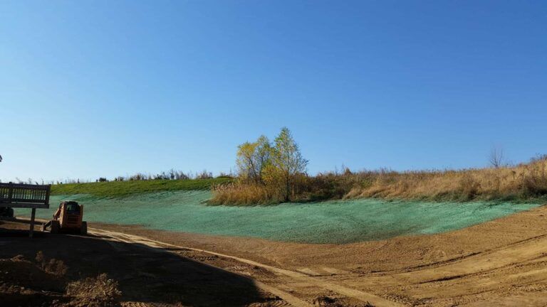 A bulldozer is working on a dirt road in a field.