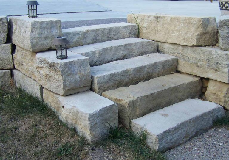 A set of stairs made of large rocks next to a stone wall.