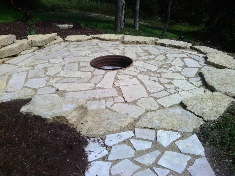 A stone patio with a fire pit in the middle