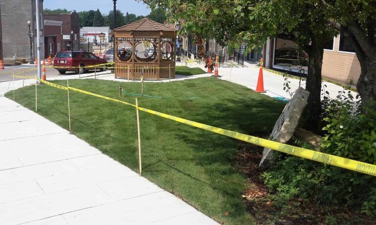 A gazebo is surrounded by yellow tape and a sidewalk