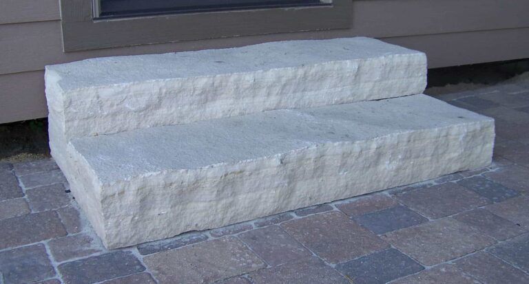 A set of stone steps sitting on top of a brick sidewalk.