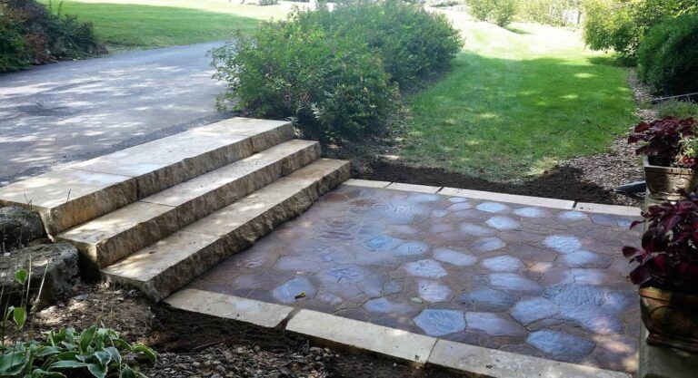 A stone walkway with steps leading up to a driveway.