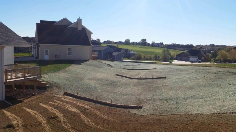 A house is sitting on top of a lush green field.