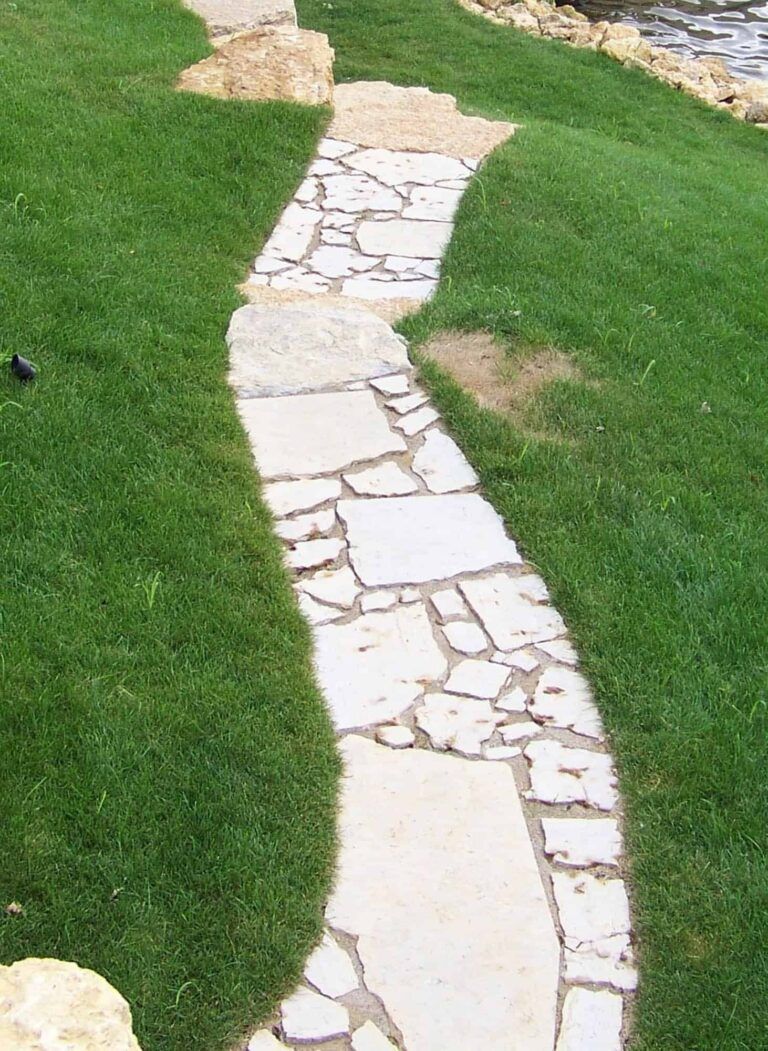 A stone walkway going through a lush green field.