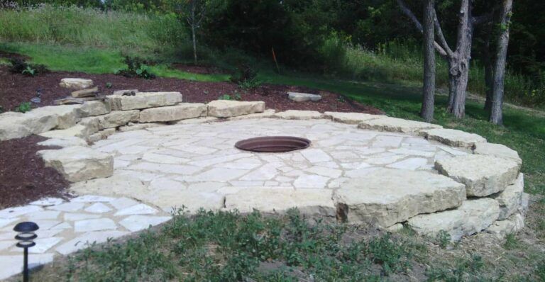A fire pit is surrounded by rocks in the middle of a yard.