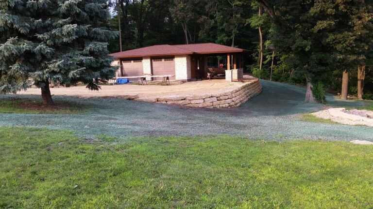 A house is sitting on top of a hill in the middle of a lush green field.
