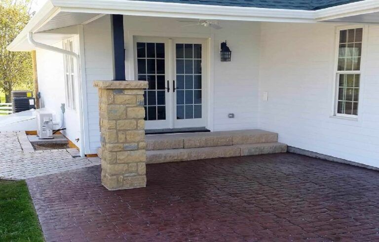 A white house with a stone pillar in front of it.