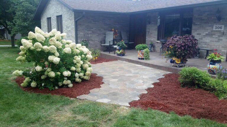 A house with a patio and flowers in front of it.