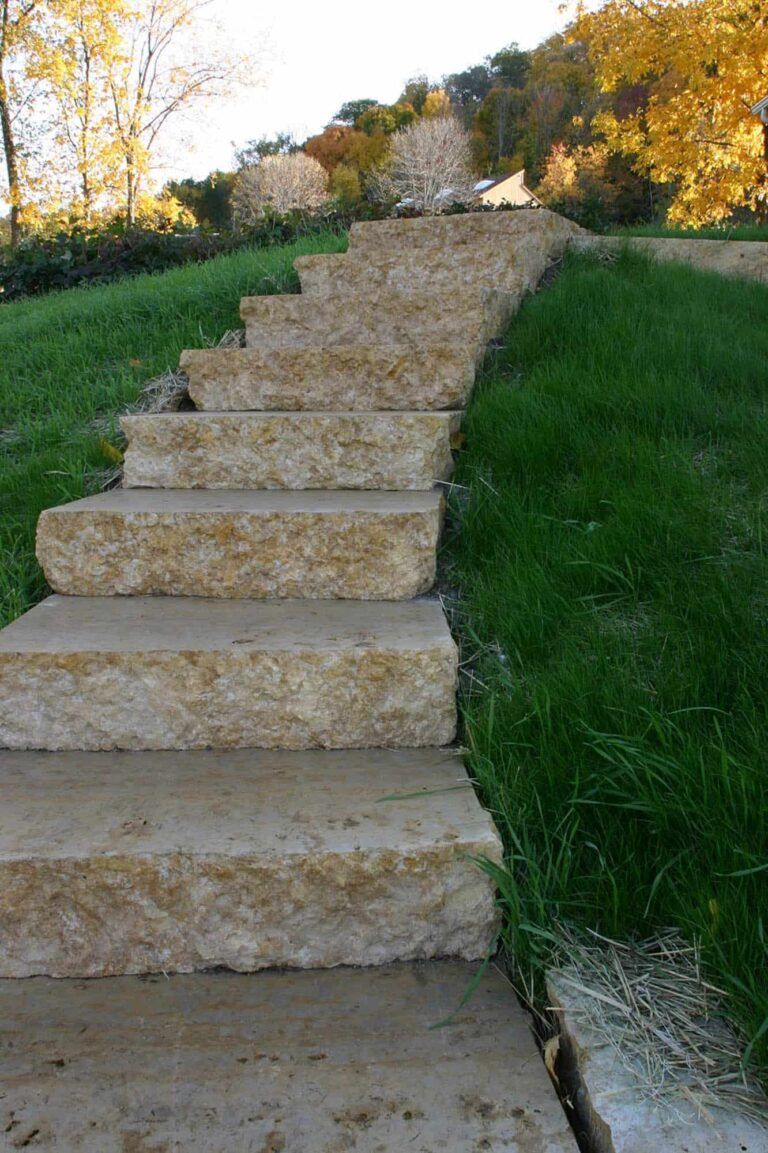 A row of stone stairs leading up to a grassy hill.