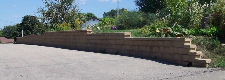 A brick wall is along the side of a road.