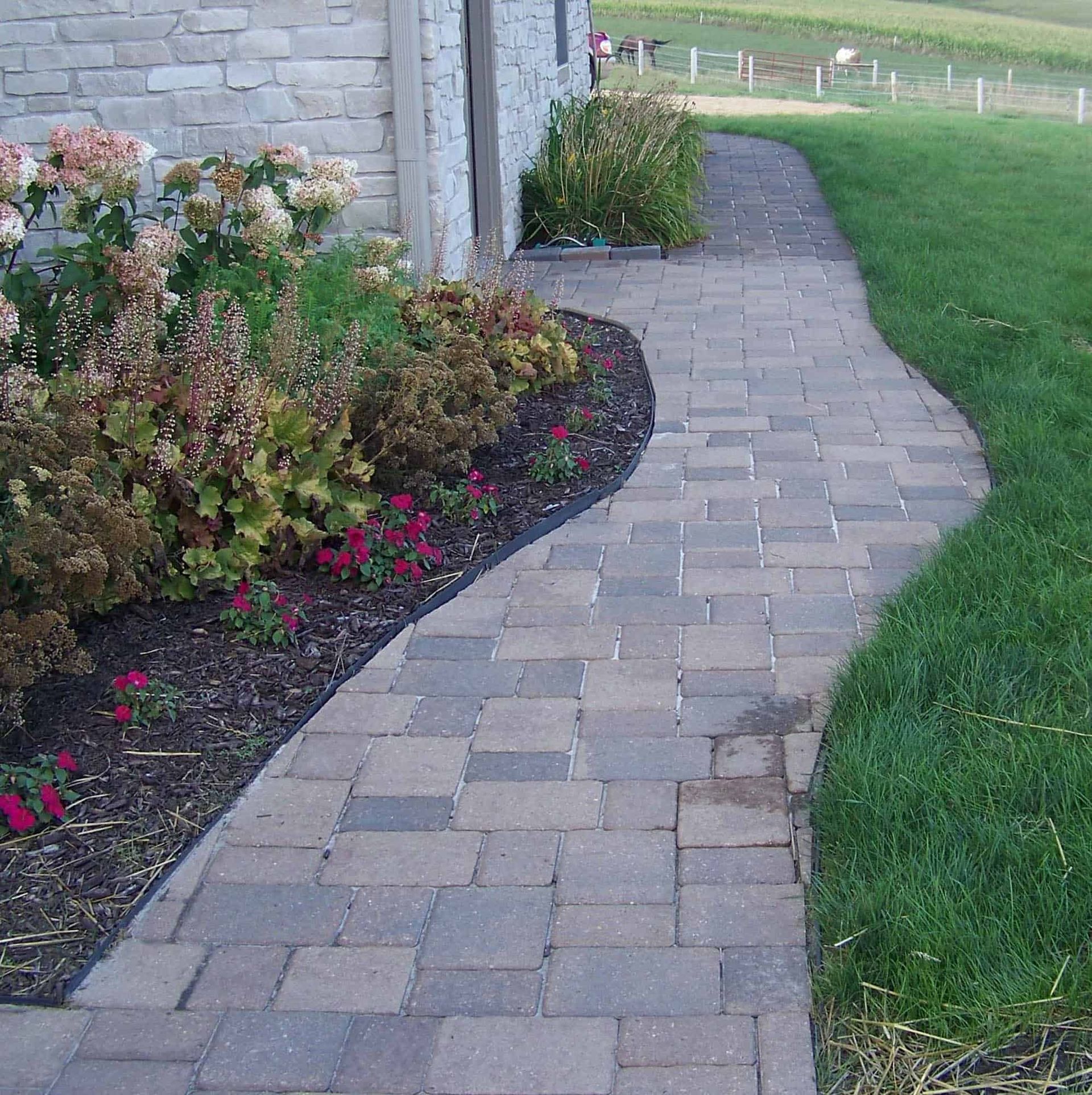 A brick walkway with flowers on the side of it