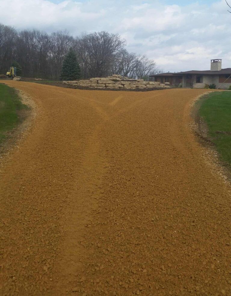 A dirt road leading to a house with a house in the background.