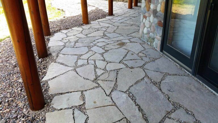 A stone walkway leading to a house with a sliding glass door.