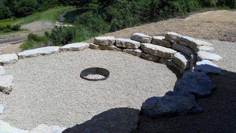 A fire pit is surrounded by rocks and gravel on a hillside.