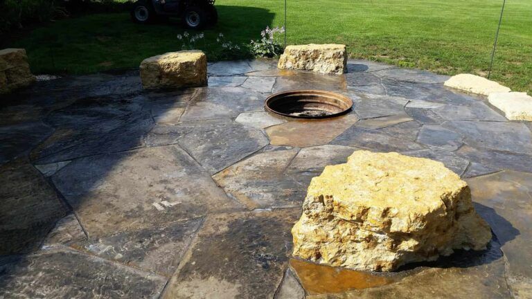 A fire pit is surrounded by rocks on a stone patio.