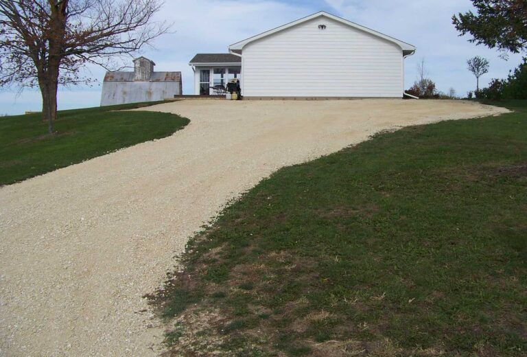 A white house with a gravel driveway leading to it
