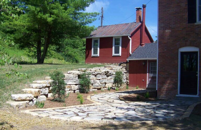 A red brick house with a stone patio in front of it