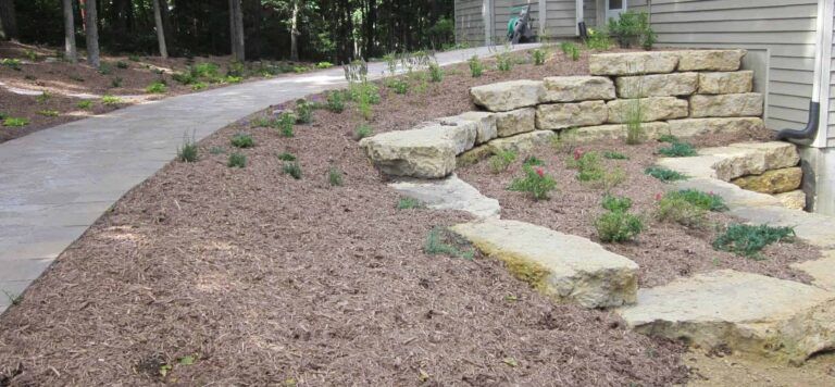 A stone wall with steps leading up to a house.