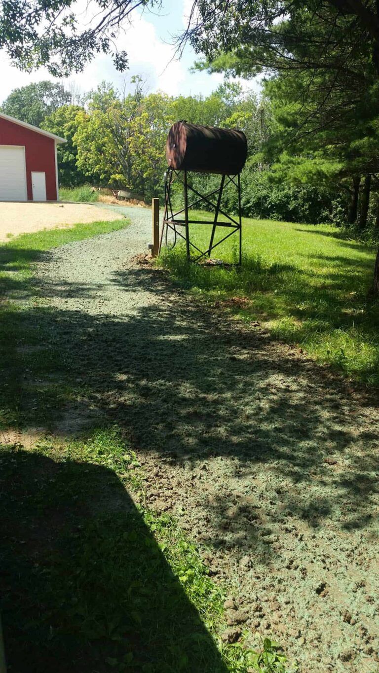 A horse is standing on a tower in the middle of a dirt road.