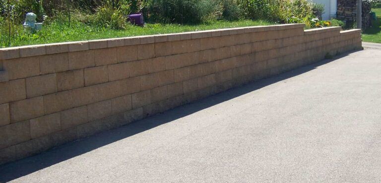 A brick wall is along the side of a road.