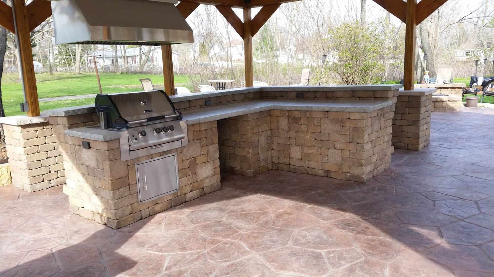 A large outdoor kitchen with a grill under a gazebo.