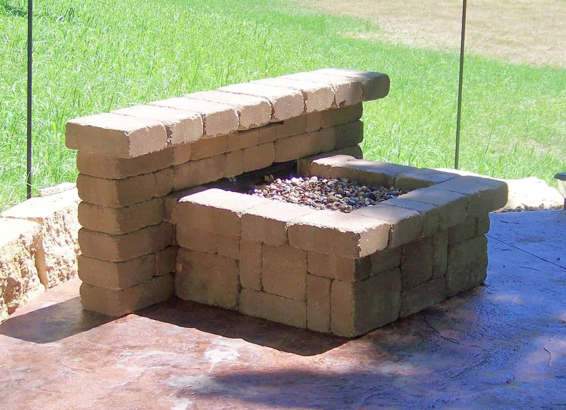 A fire pit made of bricks sits on a patio