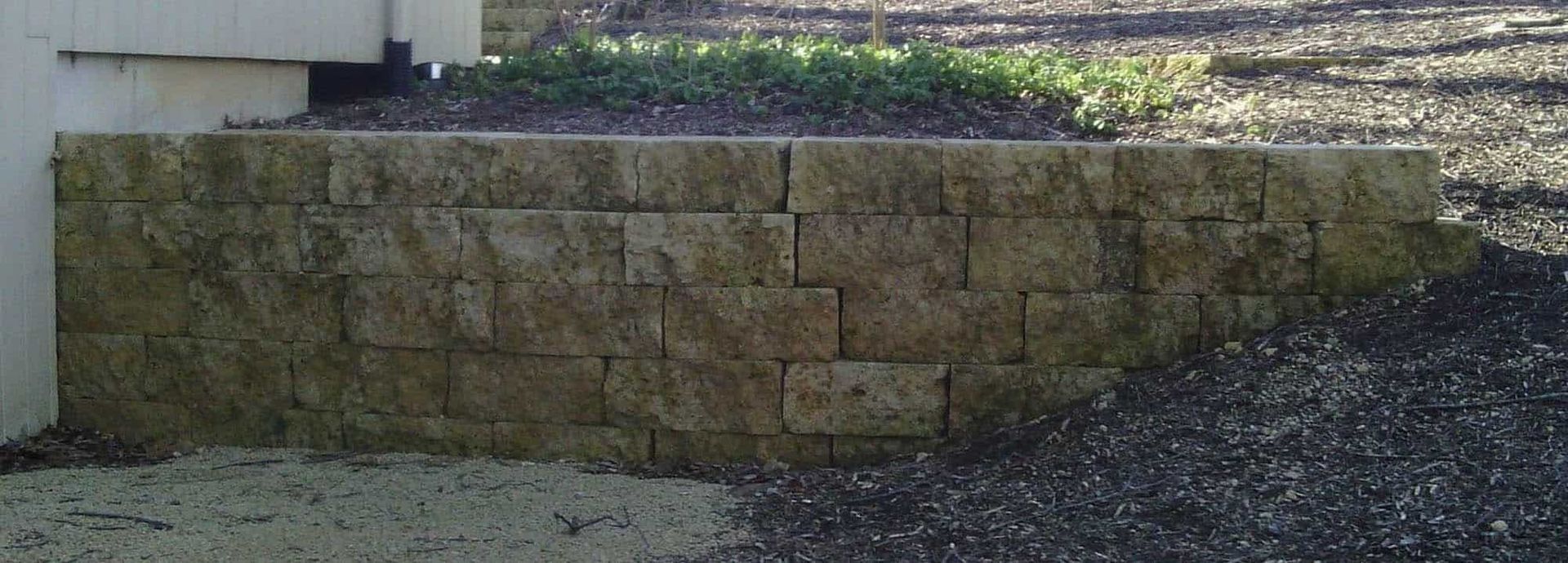A brick wall is sitting next to a gravel road.