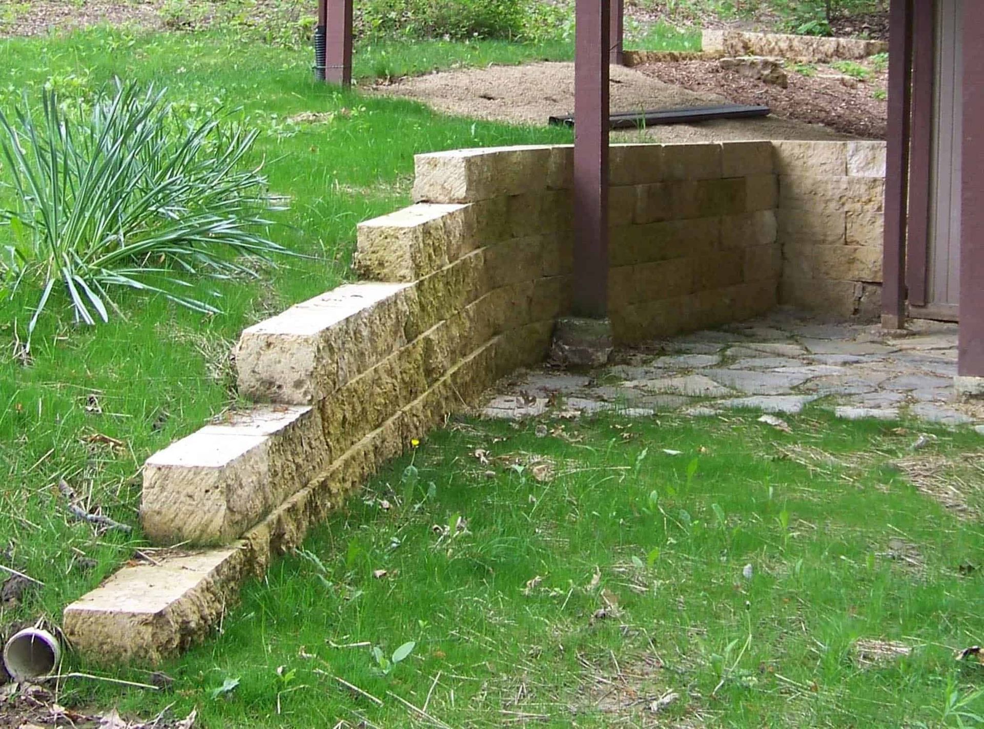 A stone wall with stairs leading up to it in a yard.