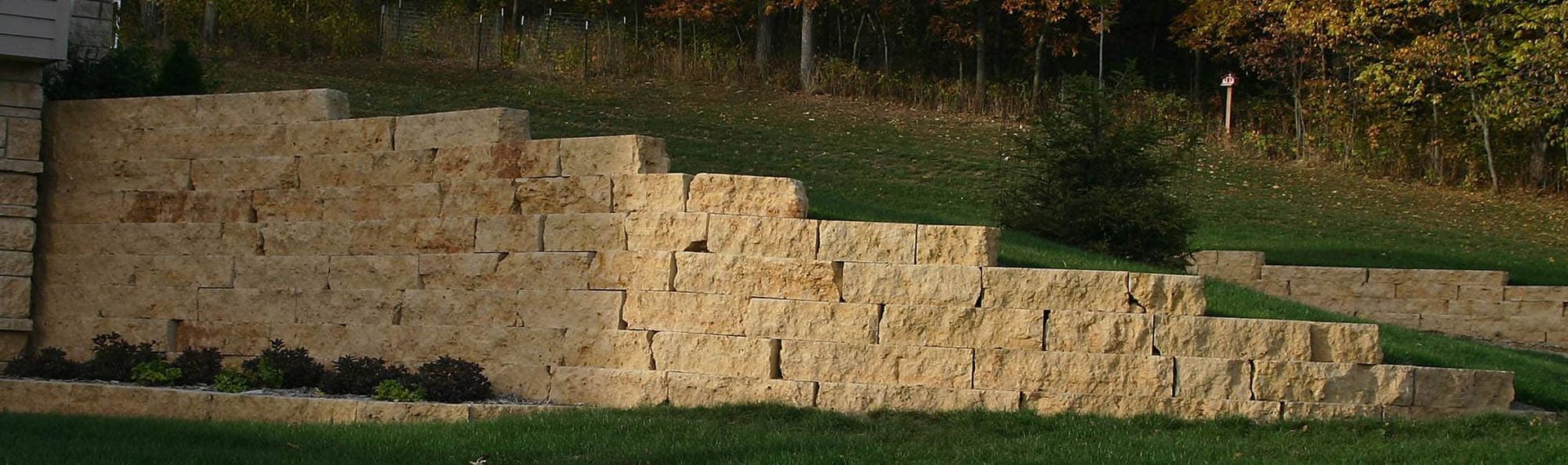 A stone wall is sitting on top of a lush green hillside.