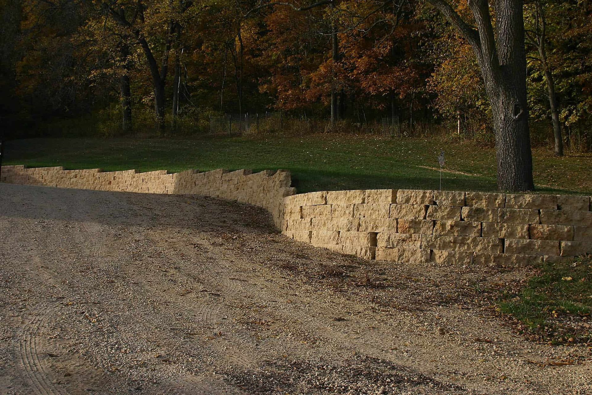 A gravel road with a stone wall on the side of it