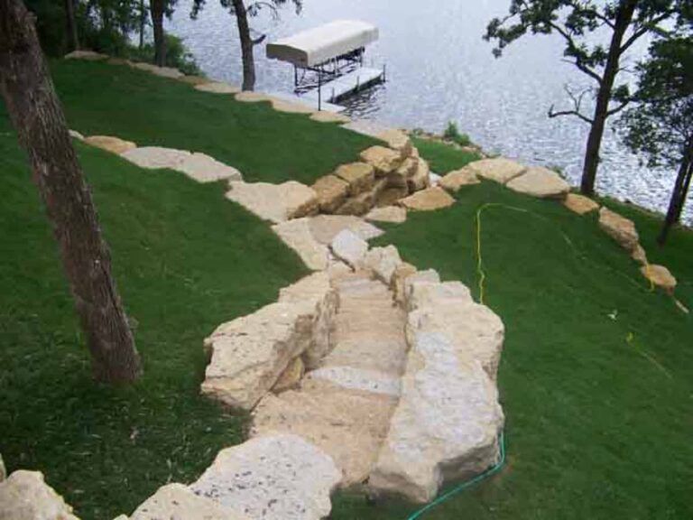 A boat with a canopy is docked on the shore of a lake