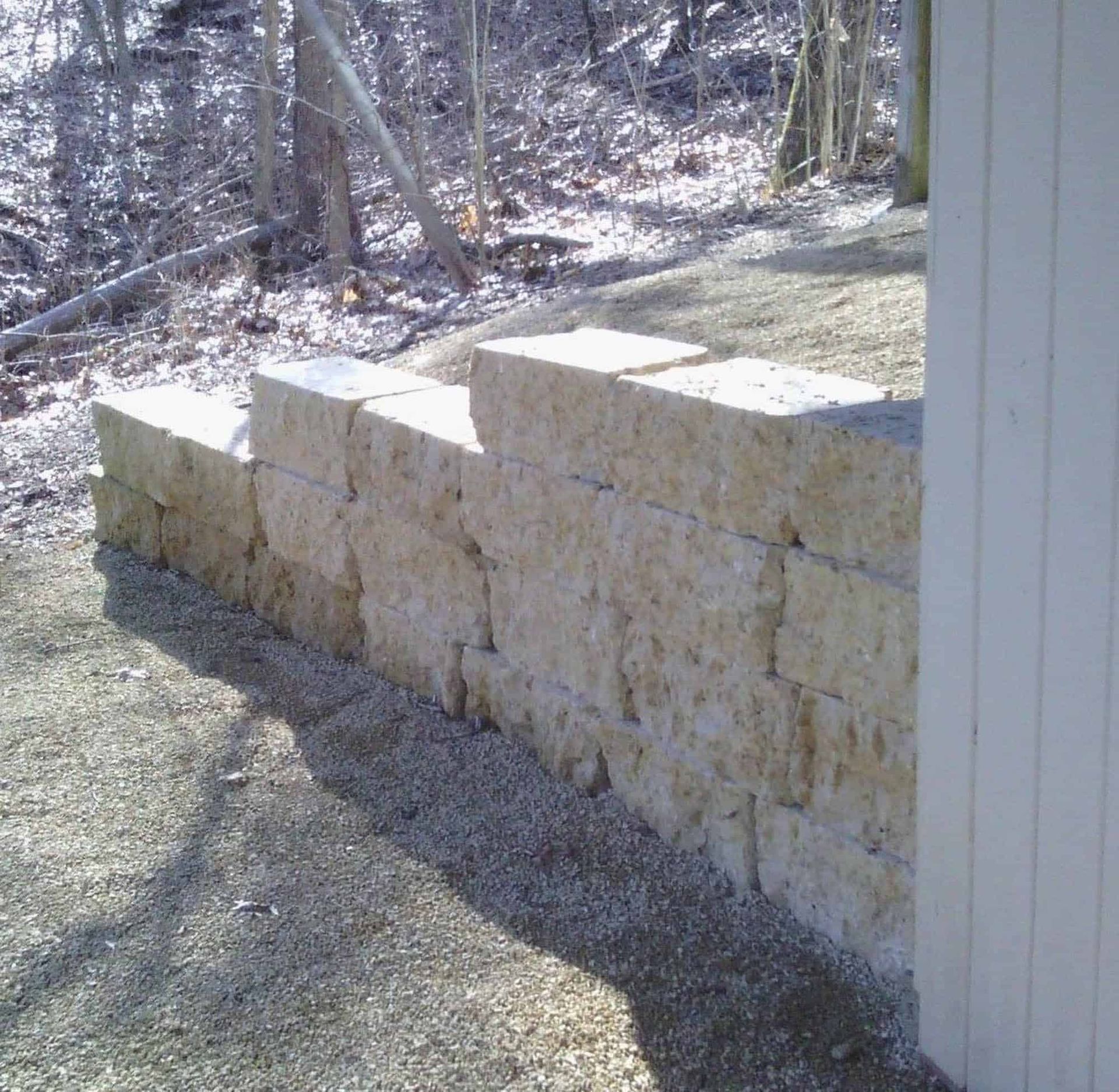 A stone wall with a white building in the background