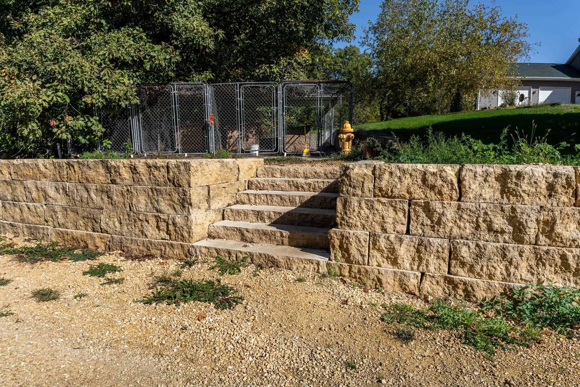 A stone wall with stairs leading up to a dog kennel.