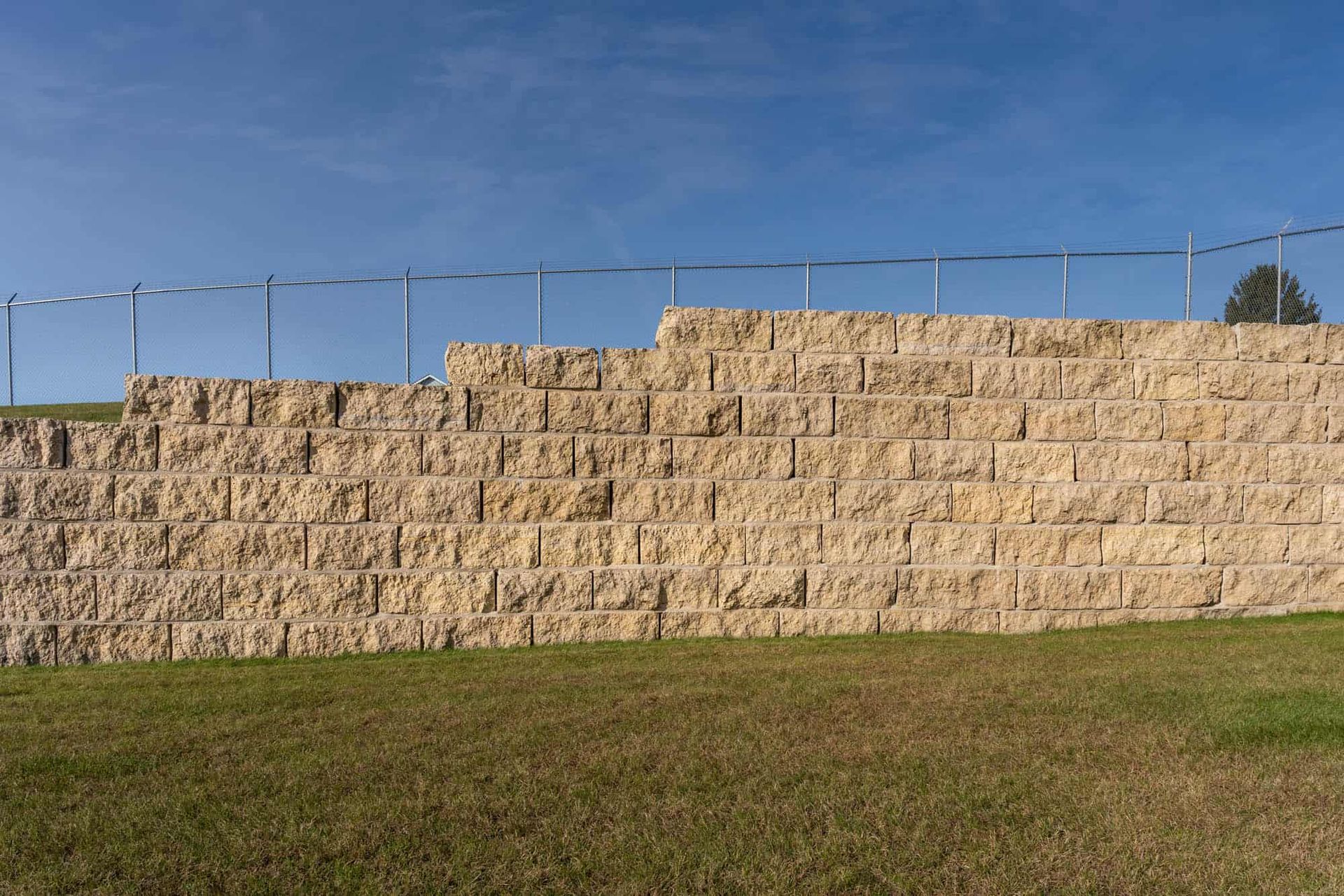 A large stone wall is sitting in the middle of a grassy field.